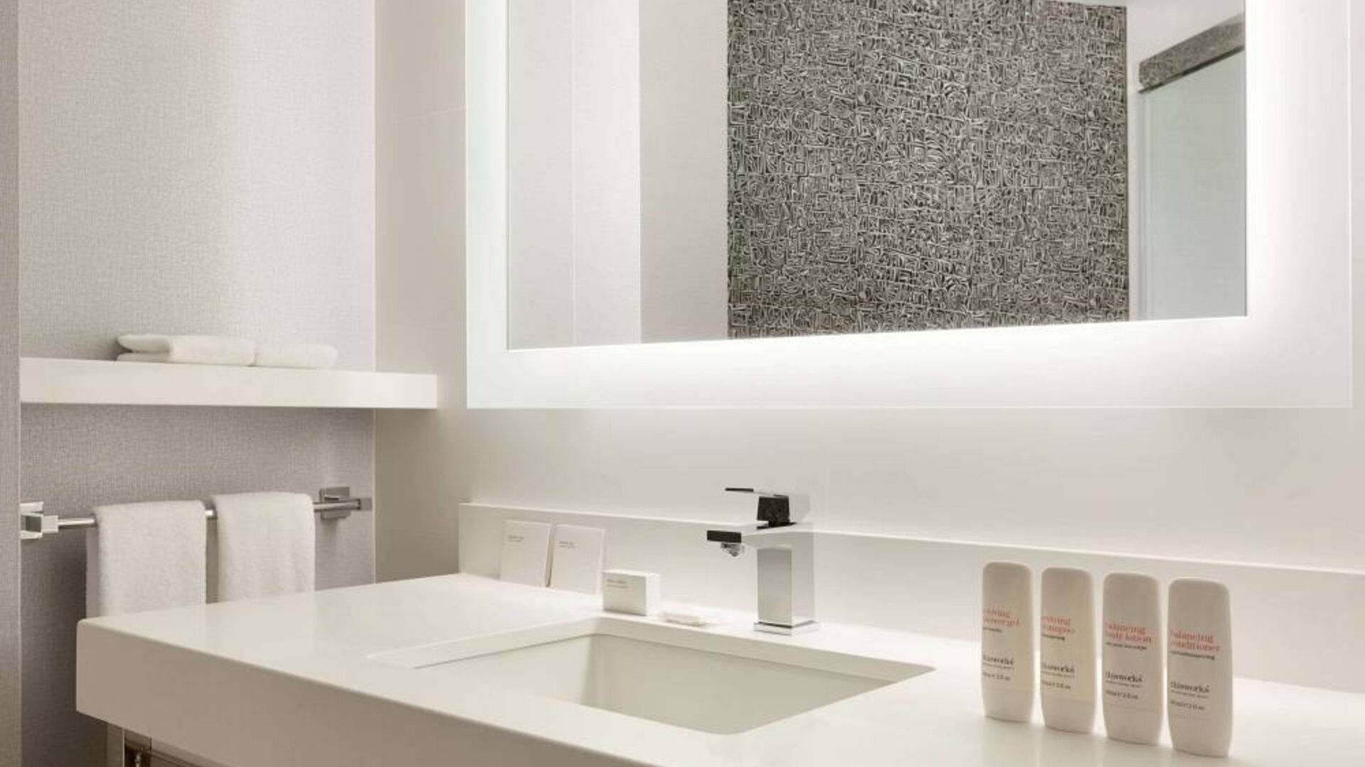 Guest bathroom in the hotel, including a range of toiletries, towels, and a sink.