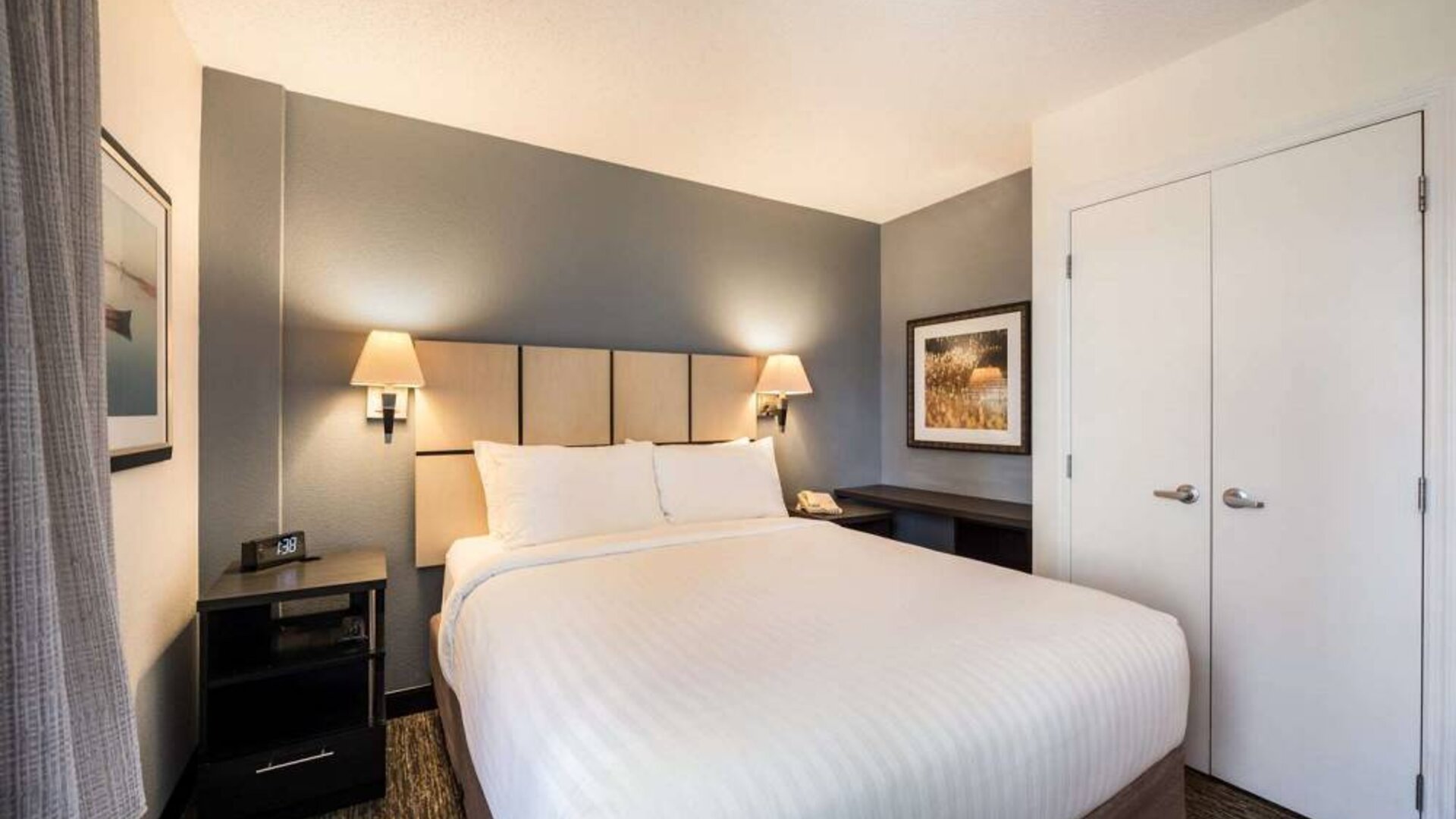 Sonesta Simply Suites Arlington double bed guest room, furnished with bedside cabinets and art on the walls.