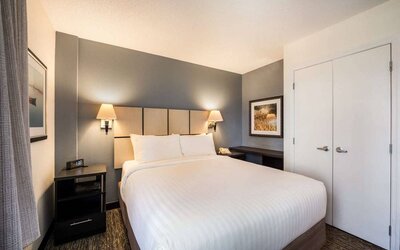 Sonesta Simply Suites Arlington double bed guest room, furnished with bedside cabinets and art on the walls.