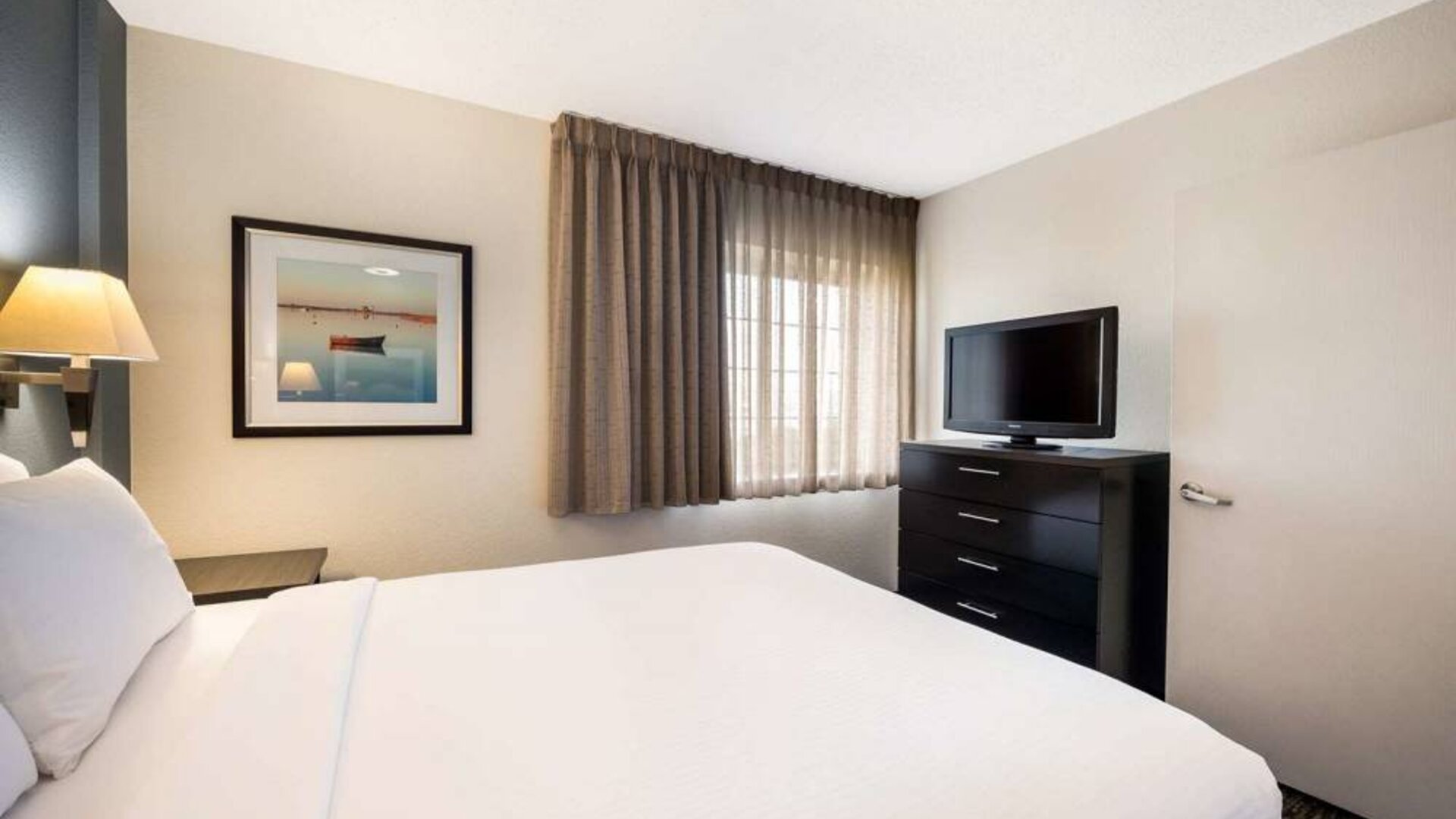 Sonesta Simply Suites Cleveland North Olmsted Airport double bed guest room, featuring widescreen TV and window.