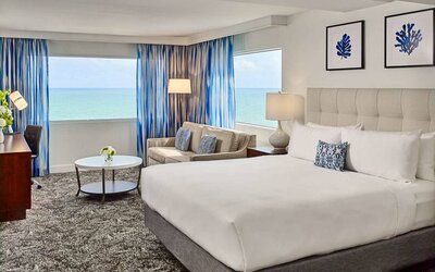 Sonesta Fort Lauderdale Beach double bed guest room, featuring ocean views, a sofa, coffee table, and workspace.