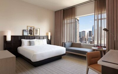 The Clift Royal Sonesta double bed guest room including sofa, window, and workspace desk and chair.