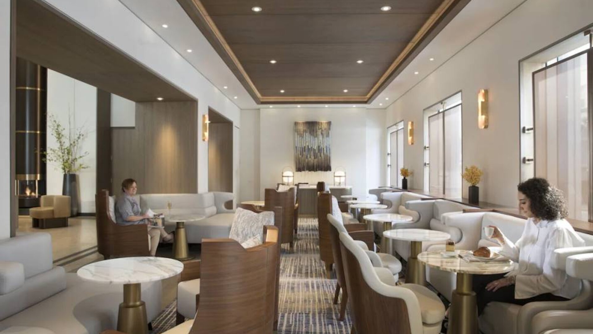 The hotel’s living room is furnished with comfortable seating and small tables, where guests can socialize, co-work, or have a drink.