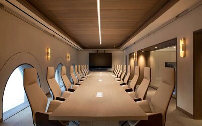 Meeting room in The Clift Royal Sonesta, featuring long table with seating for over a dozen attendees, cozy atmosphere, and large, wall-mounted TV.