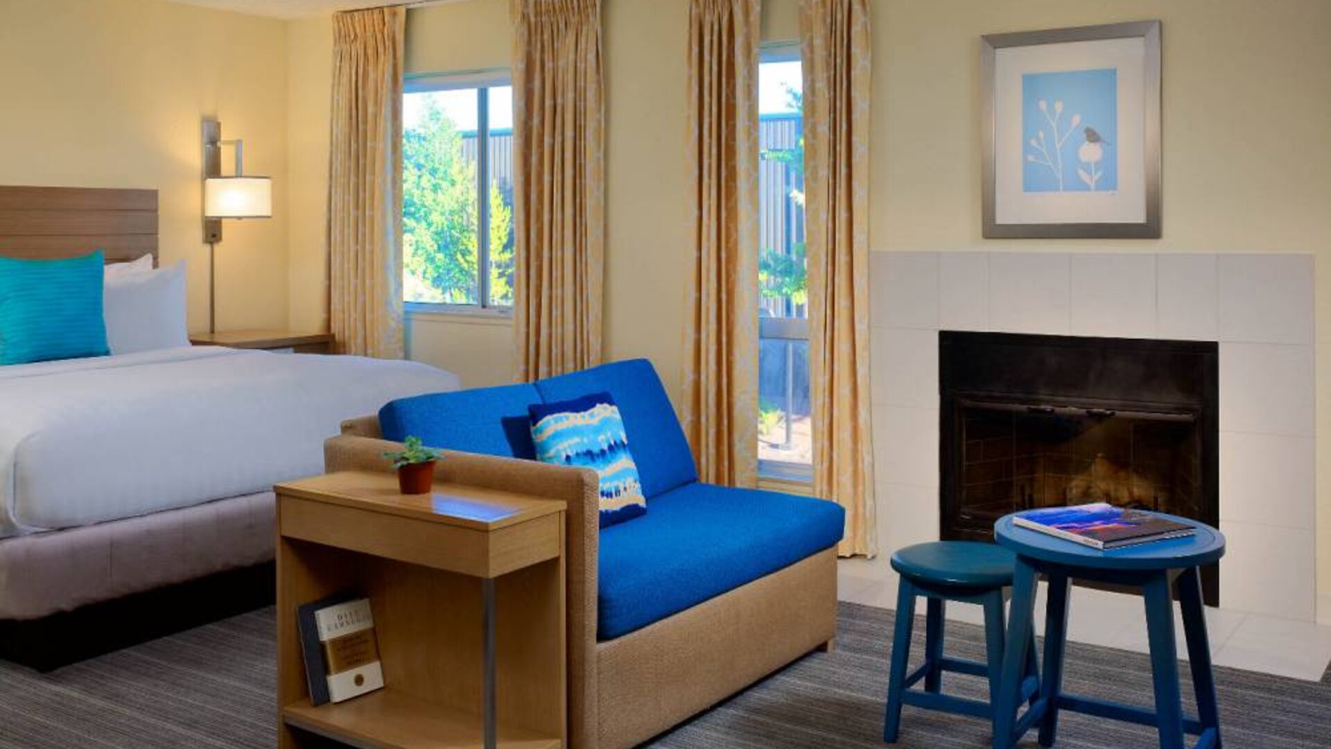 Sonesta ES Suites Flagstaff double bed guest room, featuring sofa, stool, coffee table, and fireplace.