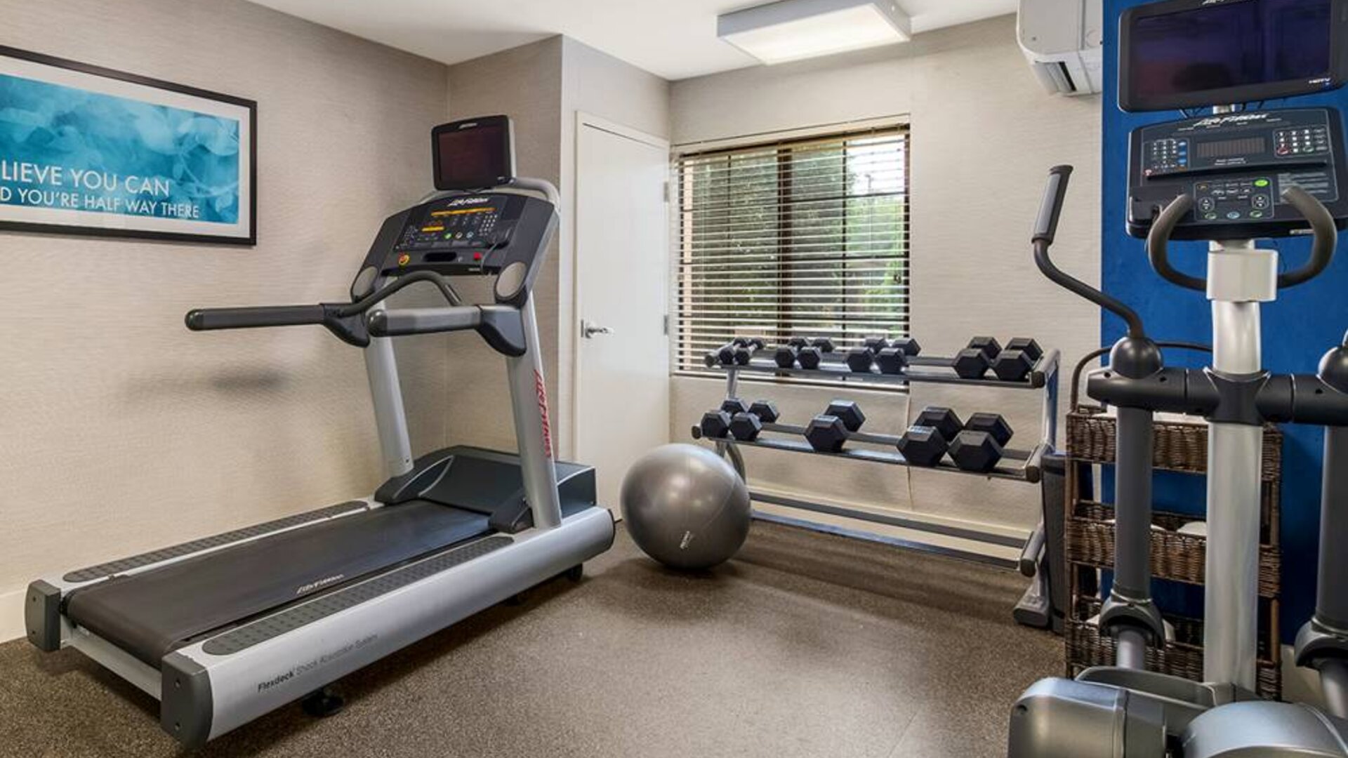 Sonesta ES Suites Charlotte Arrowood’s fitness center is equipped with rows of free weights and various exercise machines.