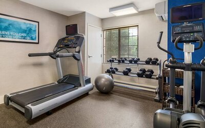 Sonesta ES Suites Charlotte Arrowood’s fitness center is equipped with rows of free weights and various exercise machines.