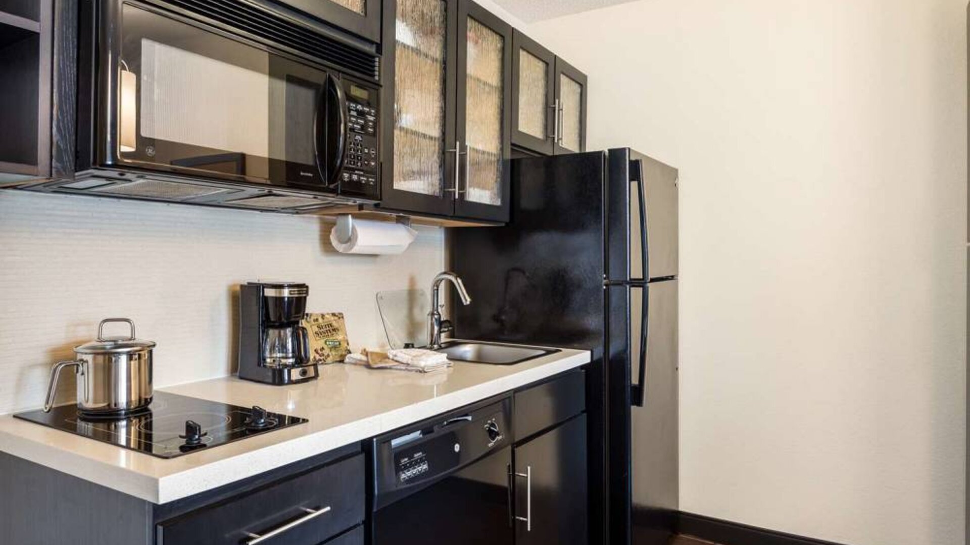 Fully equipped guest room kitchen in Sonesta Simply Suites Pittsburgh Airport, with fridge-freezer, microwave, oven, hob, and sink.