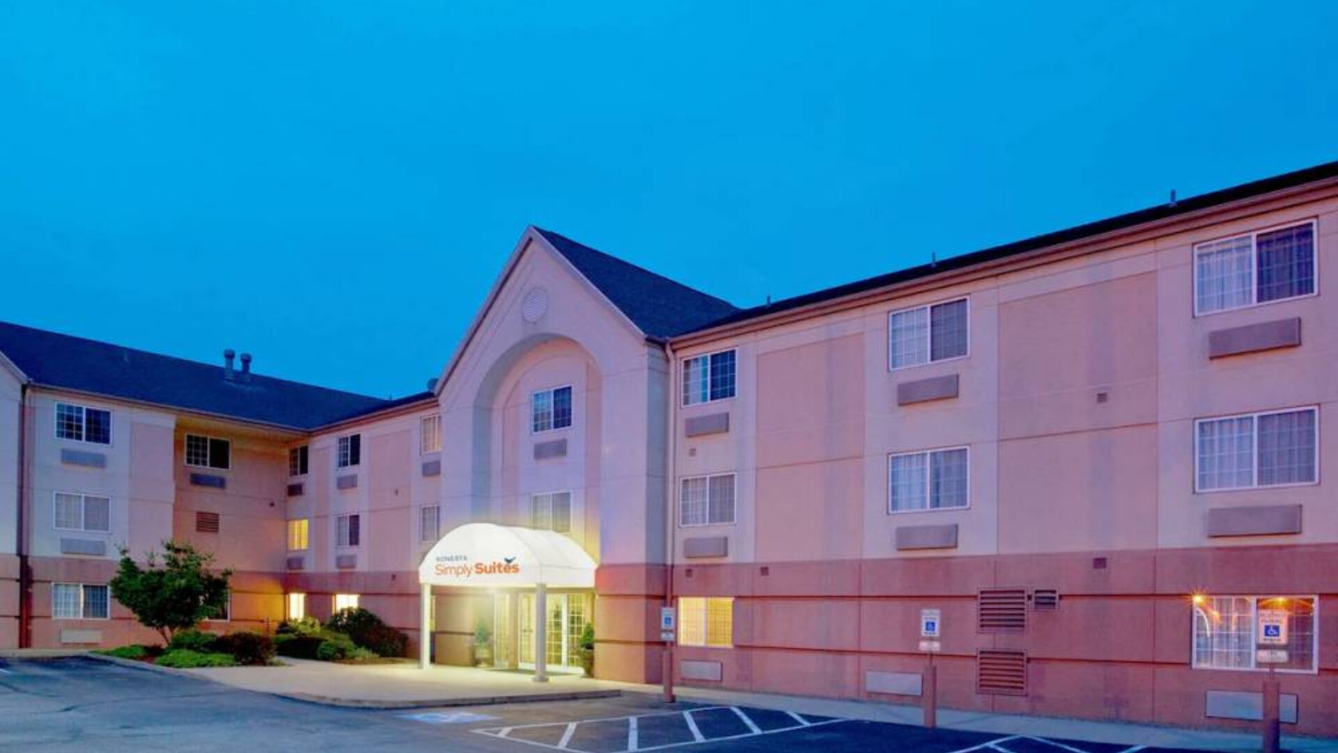 Sonesta Simply Suites Pittsburgh Airport’s exterior includes a covered entrance, pleasant greenery, and parking spaces.