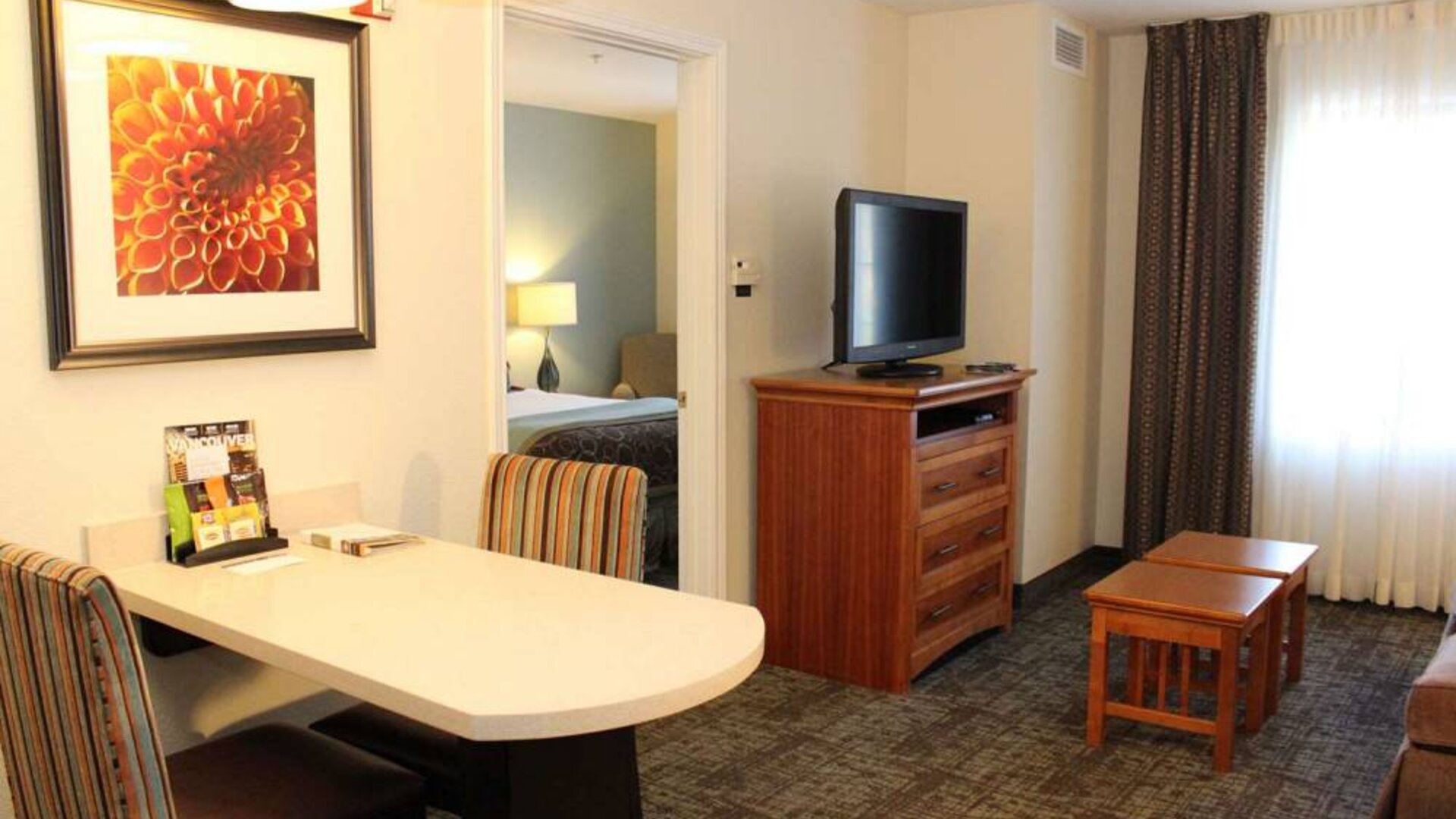 Sonesta ES Suites Portland Vancouver 41st Street guest room, furnished with double bed, desk and chairs, and a widescreen TV.
