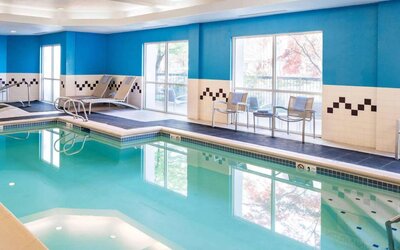 The indoor pool at Sonesta Select Seattle Renton features large windows, and has both chairs and loungers by the side.