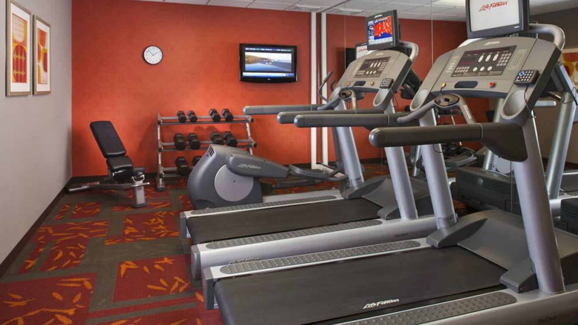 Sonesta ES Suites Birmingham Homewood’s fitness center features treadmills, an elliptical, bench, and rows of free weights, plus a TV.