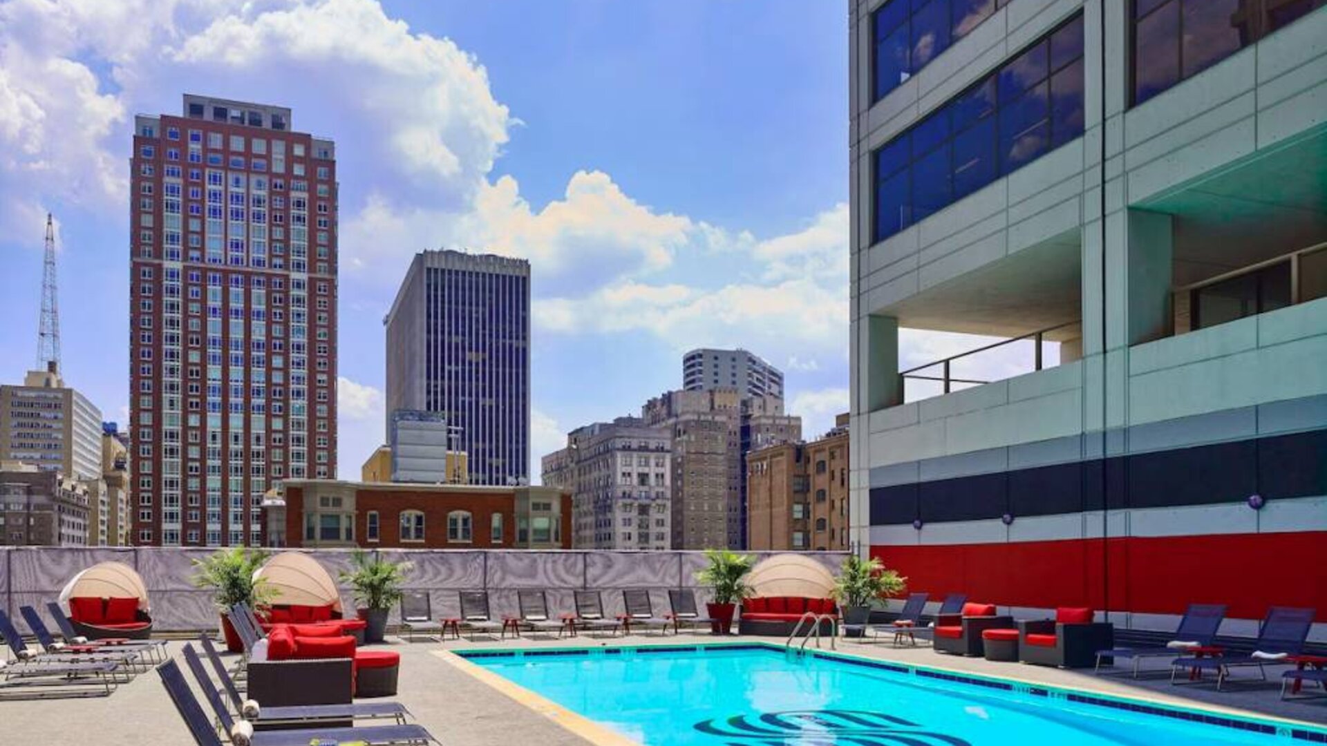 Sonesta Philadelphia Rittenhouse Square’s rooftop pool has sun loungers, armchairs, and potted plants by the side, addition to shaded seating.