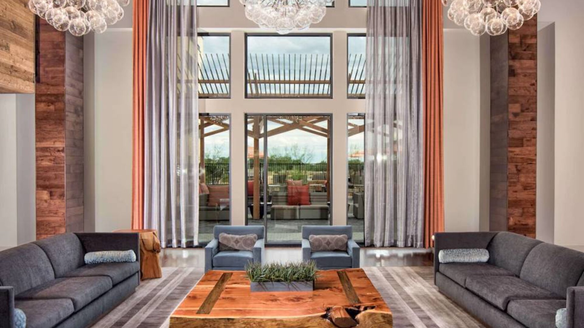 Sonesta Bee Cave Austin’s lobby lounge is furnished with armchair and sofa seating amid an airy setting, with the patio just steps away.