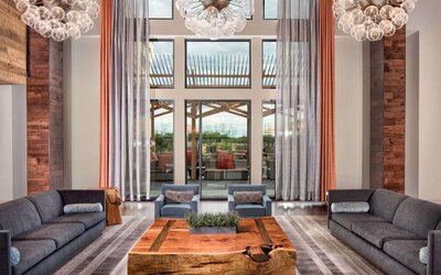 Sonesta Bee Cave Austin’s lobby lounge is furnished with armchair and sofa seating amid an airy setting, with the patio just steps away.