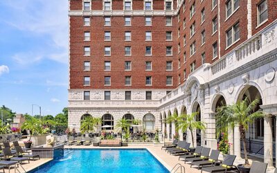 The Chase Park Plaza Royal Sonesta St. Louis’ outdoor pool has rows of sun loungers and potted palm trees by the side, plus sofa seating and a nearby patio.