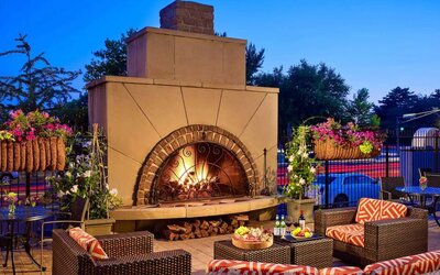 The outdoor fireplace at The Chase Park Plaza Royal Sonesta St. Louis has comfortable sofa and armchair seating nearby, in addition to coffee tables and beautiful flowers.