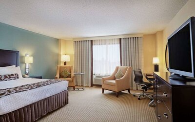 Sonesta Atlanta Airport North double bed guest room, including armchairs, window, and a television.