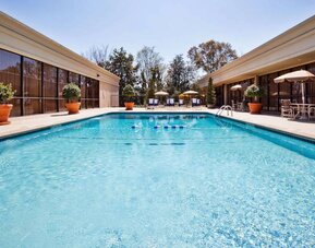 The hotel’s outdoor pool has potted plants by the side, in addition to shaded tables and chairs.