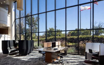 The hotel’s business center has a wall of windows next to it with a view of greenery and flags, while the center itself features multiple workstations and nooks for guests to use.