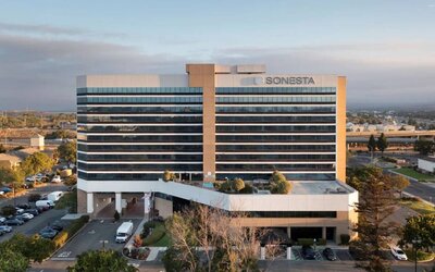 Sonesta San Jose’s exterior has ample parking for guests, abundant greenery, and a pool, plus the hotel chain’s name on the outside of the top floor.