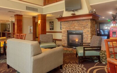 Sonesta ES Suites Anaheim Resort Area’s lobby is furnished with sofa and armchair seating around a widescreen television and fireplace.