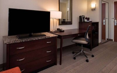 Sonesta Chicago O'Hare Airport Rosemont guest room workspace, including desk, chair, lamp, telephone, and nearby TV.