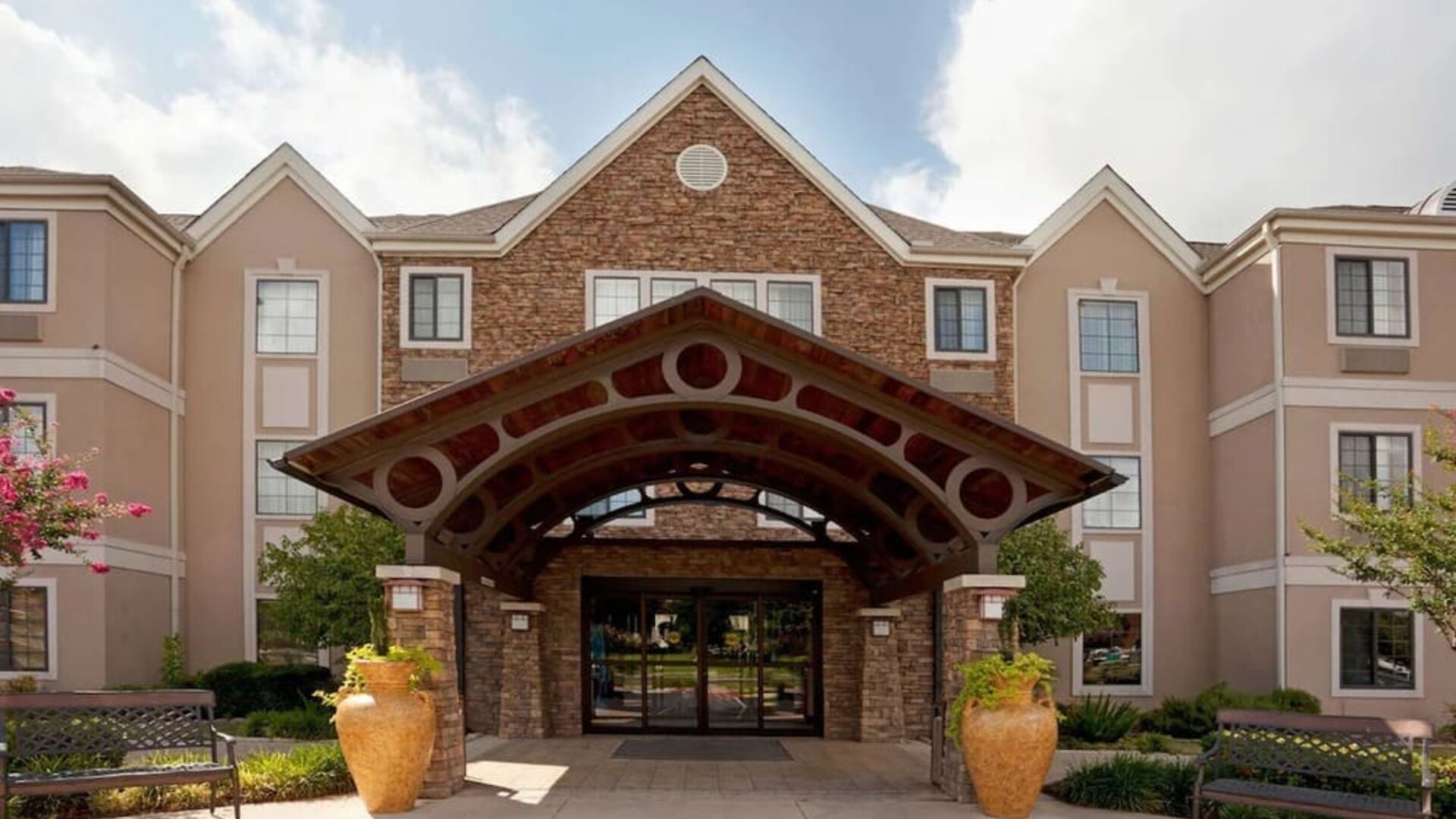 Sonesta ES Suites San Antonio Northwest - Medical Center’s exterior has pleasant greenery and benches, and a covered entranceway.