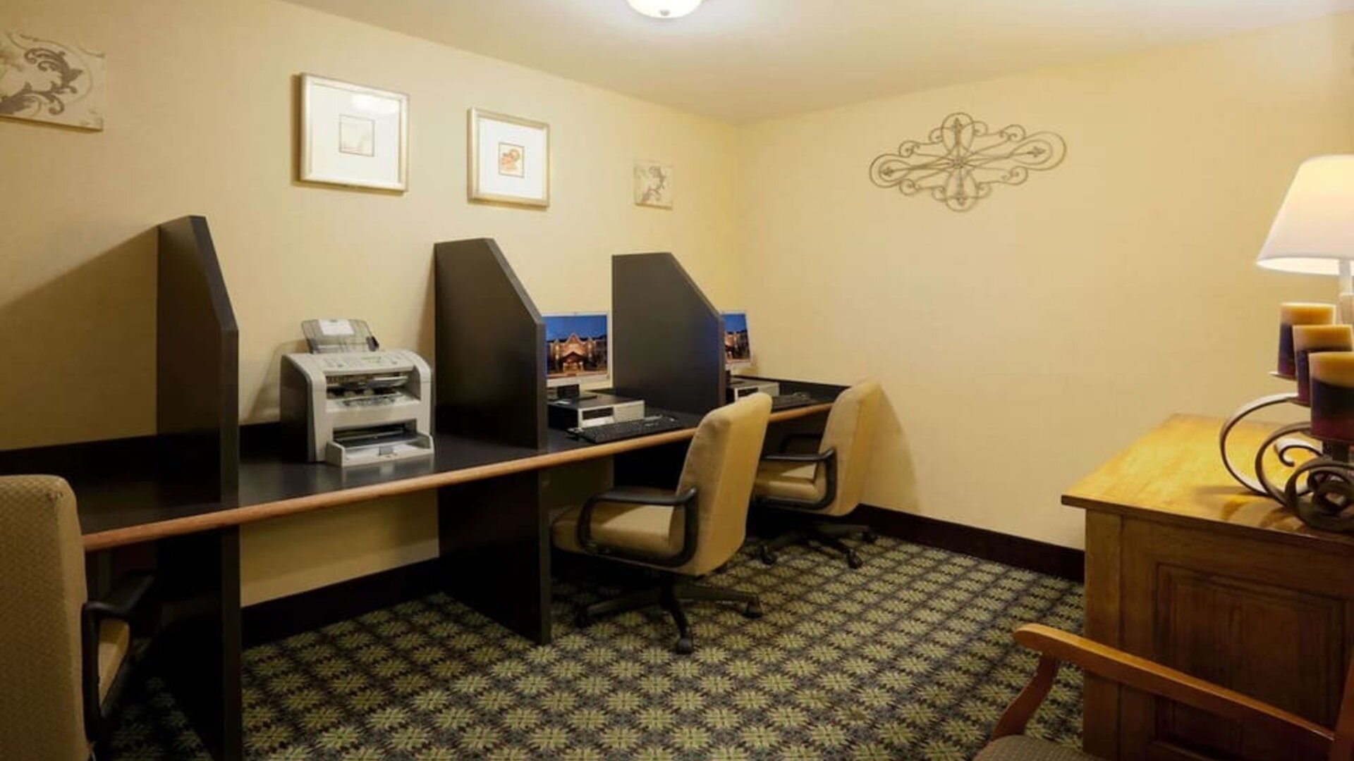 The hotel’s business center has multiple compute workstations, art on the wall, and a printer.