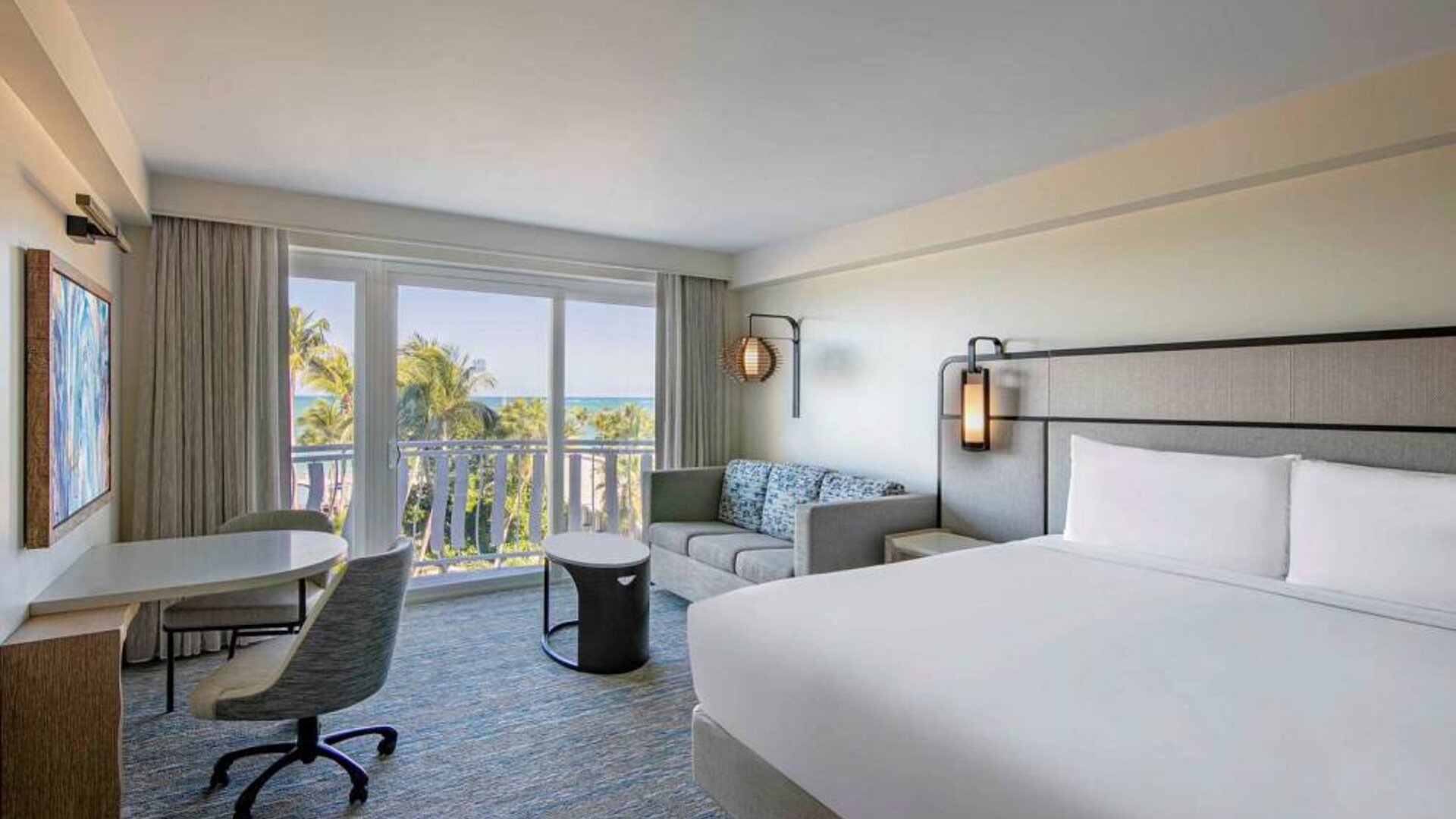 Double bed guest room in Royal Sonesta San Juan, featuring table, chairs, coffee table, and a sofa, plus balcony.