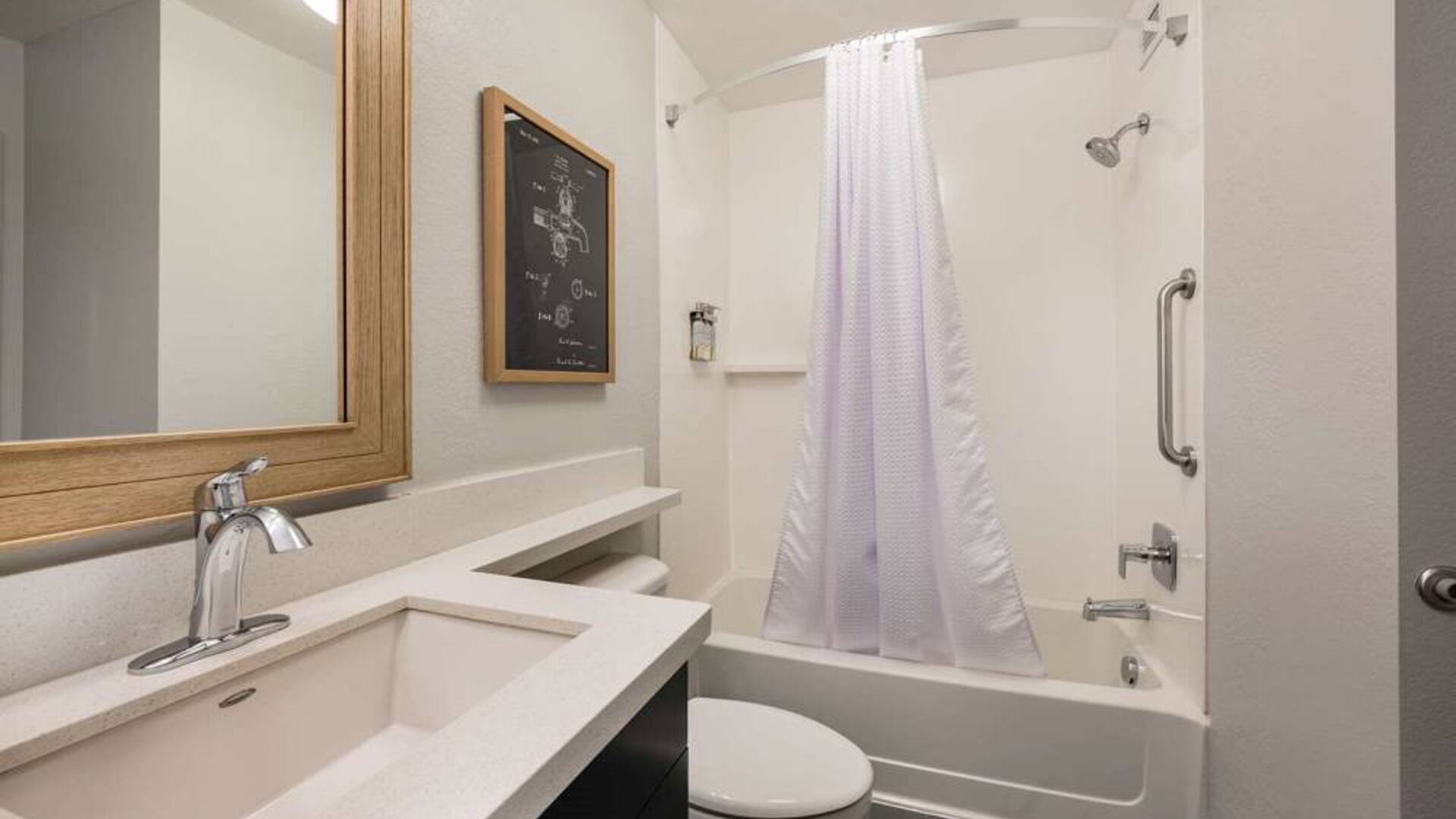 Guest bathroom in Sonesta Simply Suites Jersey City, furnished with bath and shower, lavatory, and sink and mirror.