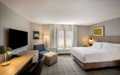 Sonesta Simply Suites Jersey City double bed guest room, featuring armchair, window, and widescreen television.