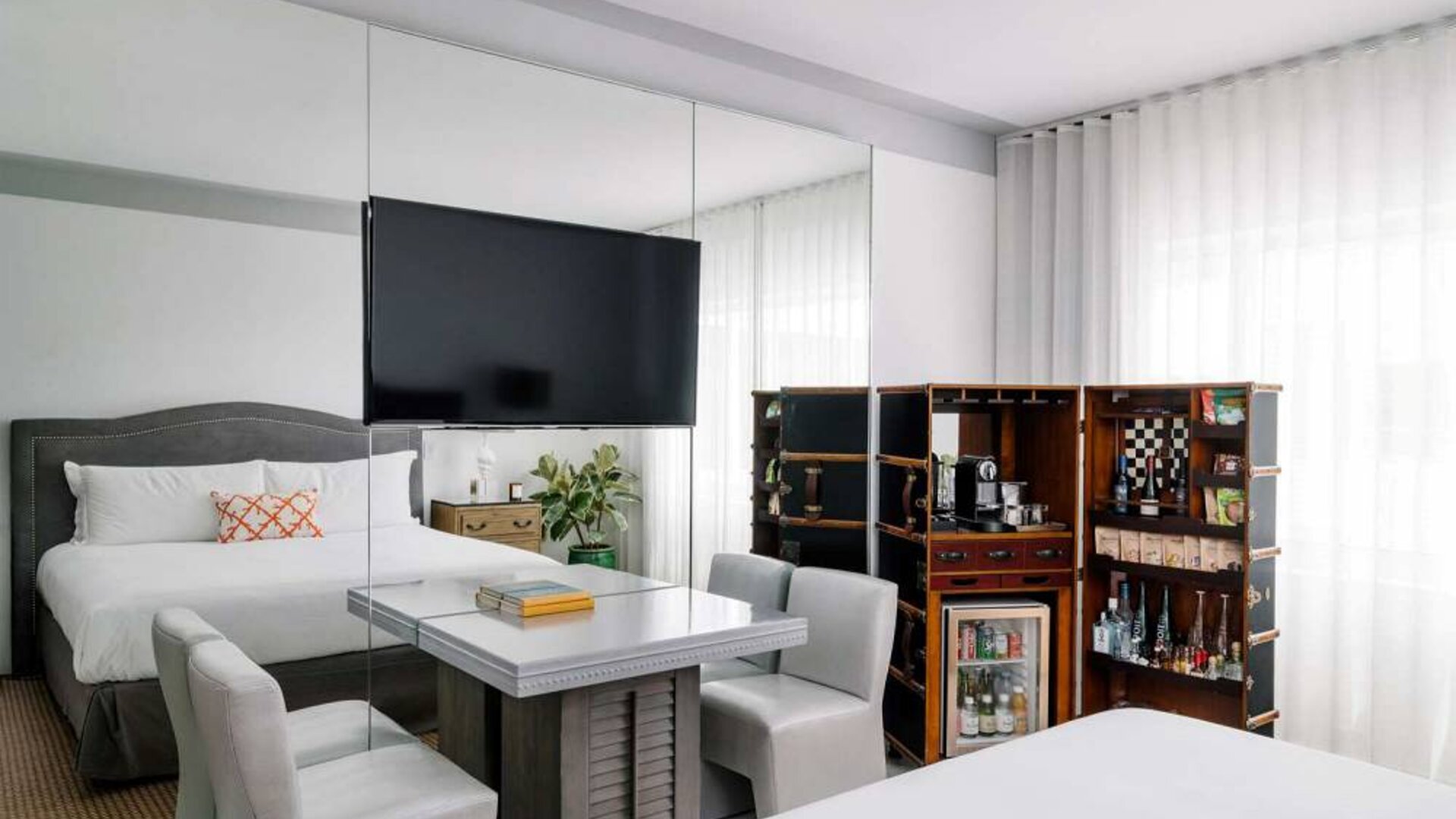 Nautilus by Sonesta double bed guest room furnished with table, chairs, mini-fridge, and a widescreen TV.