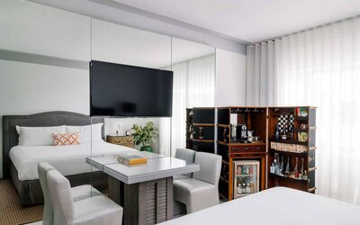 Nautilus by Sonesta double bed guest room furnished with table, chairs, mini-fridge, and a widescreen TV.