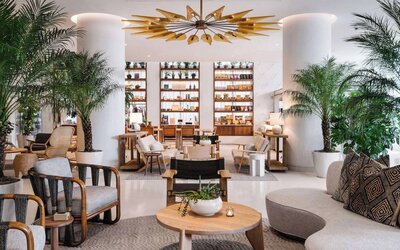 Nautilus by Sonesta’s lounge area provides both armchair and sofa seating, with coffee tables and many potted plants nearby.