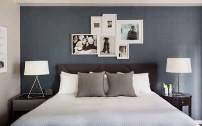 The Shelburne Sonesta New York double bed guest room, with art on the walls and bedside lamps.