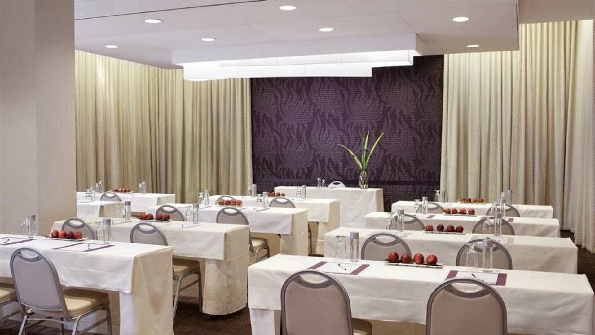 The Shelburne Sonesta New York meeting room with tables arranged in a classroom style facing a head table and space for over a dozen attendees.
