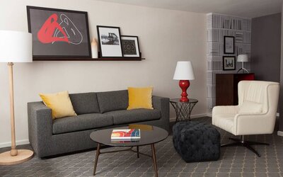 The Fifty Sonesta Select New York guest room living area, furnished with sofa, chair, coffee table, and artwork.