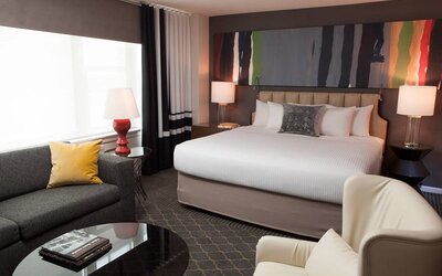 Double bed guest room in The Fifty Sonesta Select New York, with sofa, chair, coffee table, and large window.