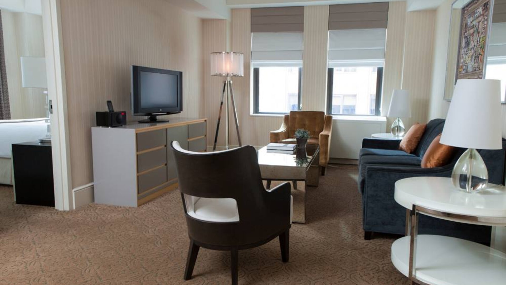 The Benjamin Royal Sonesta New York guest room, featuring chairs, sofa, coffee table, windows, and a television.