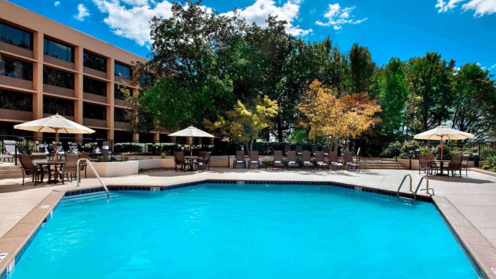 Sonesta Nashville Airport’s outdoor pool has shaded tables and chairs nearby, alongside a row of sun loungers.