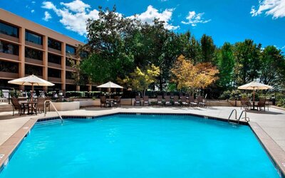 Sonesta Nashville Airport’s outdoor pool has shaded tables and chairs nearby, alongside a row of sun loungers.