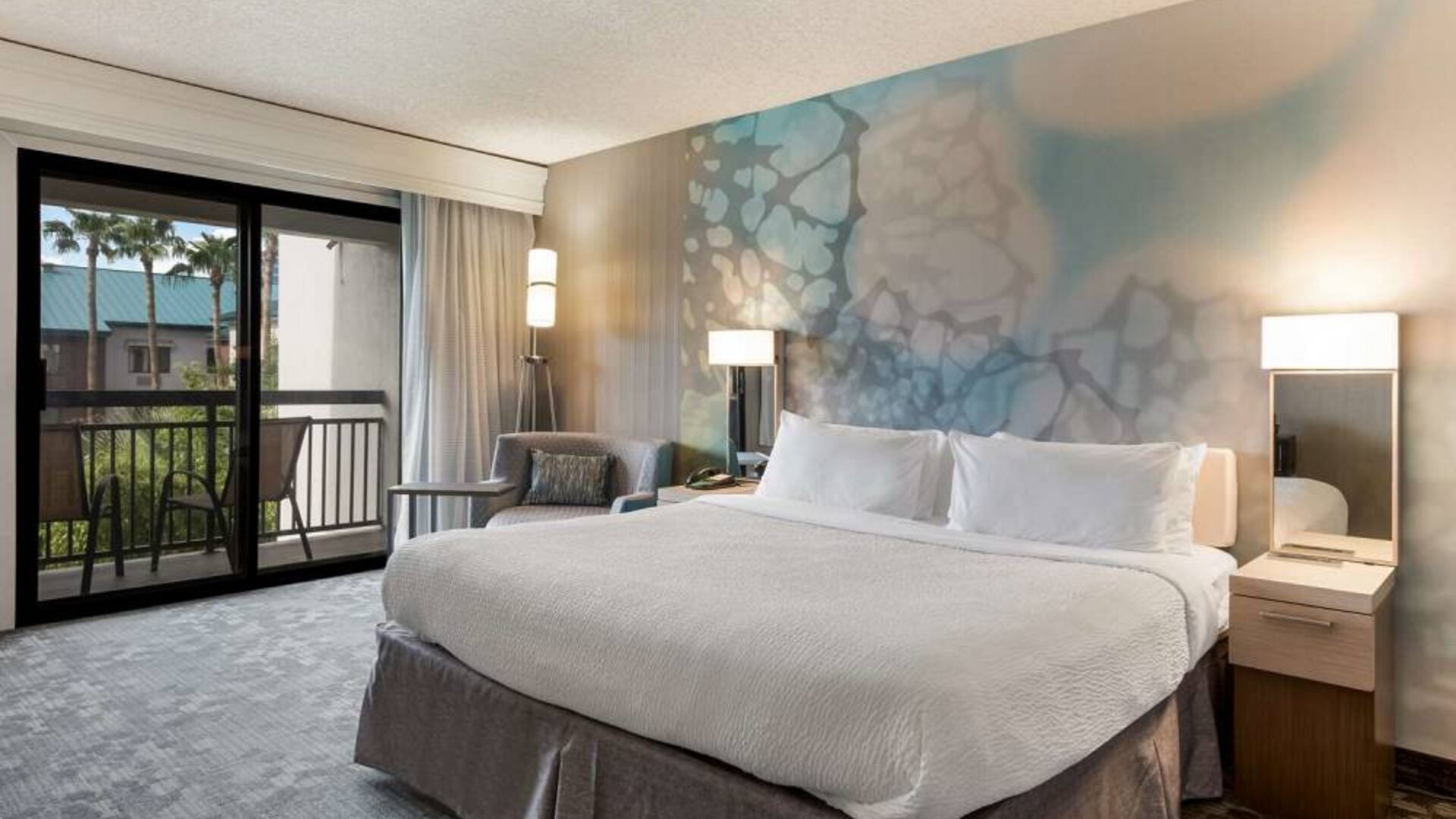 Double bed guest room in Sonesta Select Tempe Downtown, featuring armchair, coffee table, and balcony.