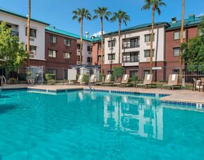 The hotel’s outdoor pool has loungers, as well as a table and chairs, by the side, plus towering trees beyond the fence.