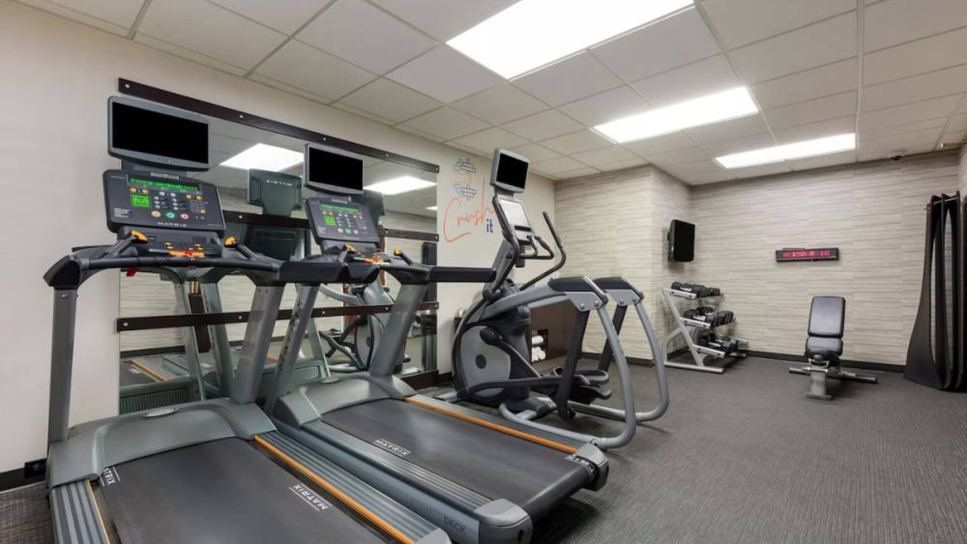 The fitness center in Sonesta Select Tempe Downtown has a wall-mounted TV, free weights, and exercise machines facing a large mirror.