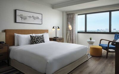 Double bed guest room in Sonesta Irvine, featuring art on the wall, chair, and window.