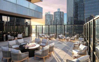 The hotel terrace offers elevated city views and comfy seating beside coffee tables, plus a fire pit.