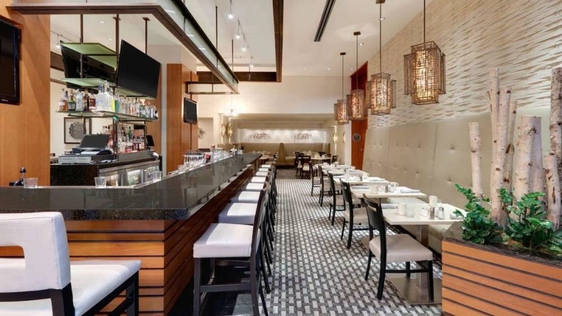 The hotel’s restaurant offers on-site dining, a mix of bar stools alongside small tables and chairs, and multiple widescreen televisions.