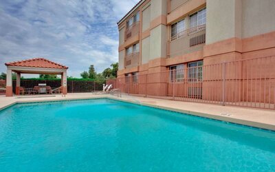 The outdoor pool at Sonesta Simply Suites Phoenix Tempe has sun loungers by the side, and is close to the gazebo and barbecue facilities.