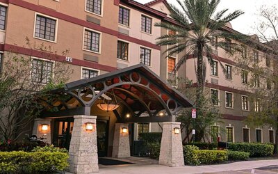 The hotel’s exterior features a covered entrance beside which there’s extensive greenery, including a towering palm tree.